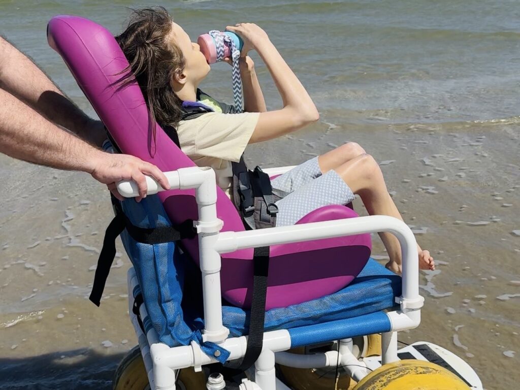 teenager with disabilities drinking from Replay no-spill cup at the beach — sippy cups for special needs