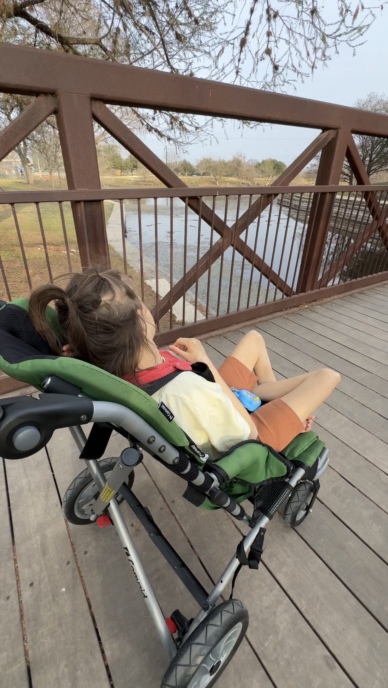 Convaid cruiser green stroller outdoors being used by a bigger disabled kid