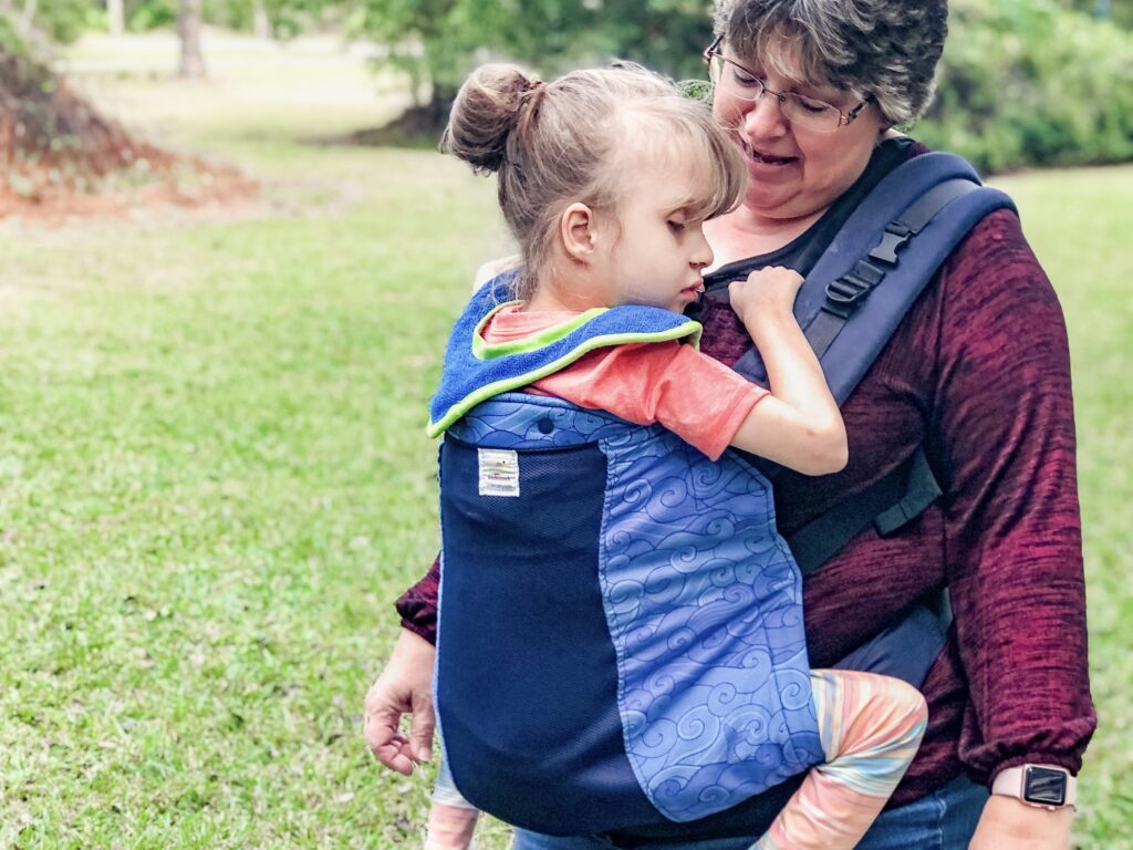 grandparent wearing a baby carrier for bigger kids in the blue wave print from Kinderpack